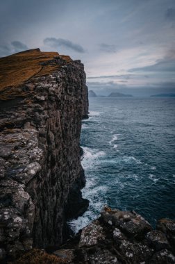 Faroe Adaları Traelanipa. Kölelerin kaya uçurumu okyanusun üzerinde Sorvagsvatn Gölü 'nün yanında yükseliyor. Sonbahar boyunca Faroe Adaları 'ndaki vajina adasında bulutlar ve mavi gökyüzü. Kasım 2021