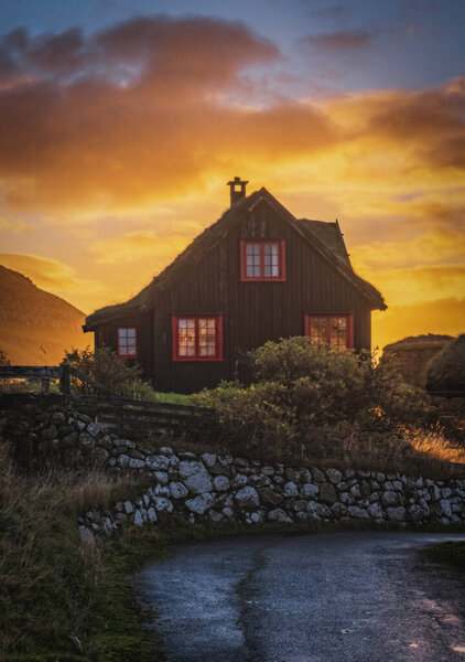 Старый бревенчатый фермерский дом Кирхьюборгардур с терновой крышей в деревне Киркджубур на Стреймой, Фарерские острова. Восход солнца, ноябрь 2021