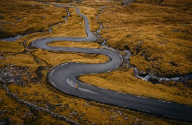 Aerial view on serpentine road on the island Streymoy near the village Nordradalur with view of Koltur island. Faroe Islands, Denmark. November 2021. Lonely wanderer on serpentine road clipart