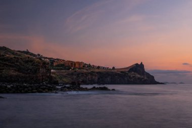 Canico de Baixo ve Reduto 'nun kıyı şeridi güneş doğarken Portinho' yu sallıyor. Madeira, Ekim 2021. Uzun pozlama resmi