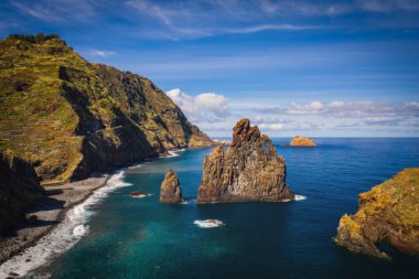 View of the Ilheus da Ribeira da Janela rock islets under a clear blue sky. The rocks form a famous landmark on the northern shore of the island of Madeira, Portugal. Aerial drone shot, october 2021