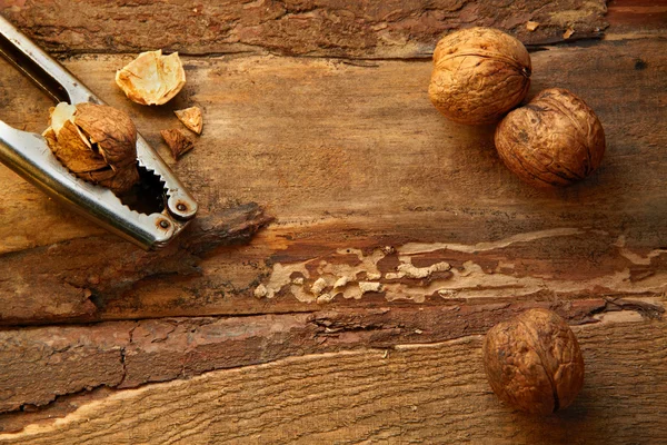Walnuts and nutcracker on wooden background — Stock Photo, Image