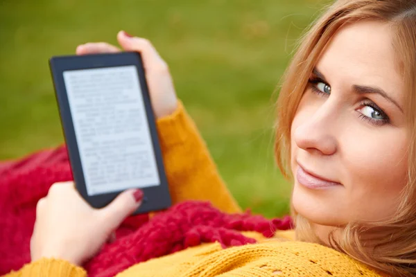 Mulher está lendo o e-book deitado na rede Fotografias De Stock Royalty-Free