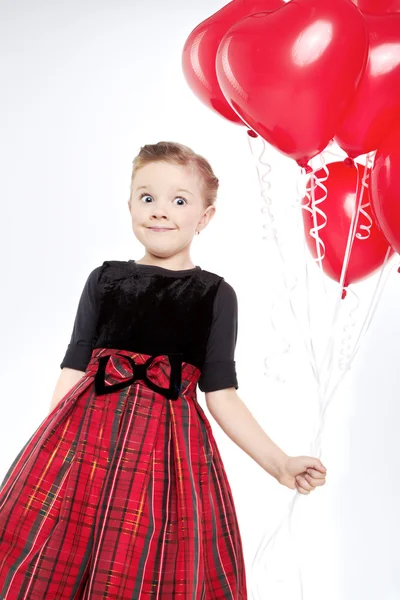 Menina bonito segurando um monte de balões em forma de coração vermelho — Fotografia de Stock