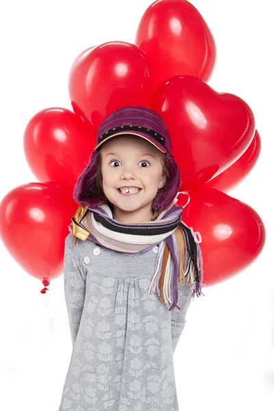 Linda niña sosteniendo un montón de globos rojos en forma de corazón —  Fotos de Stock