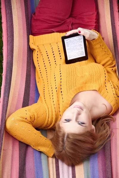 Woman is reading the e-book lying on the hammock — Stock Photo, Image