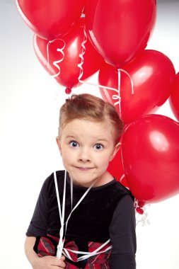 sevimli küçük kız elinde bir demet kırmızı kalpli balon