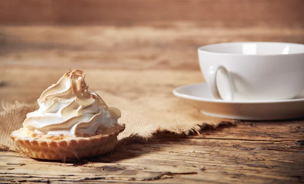 Zoete cake met kopje thee op houten tafel — Stockfoto