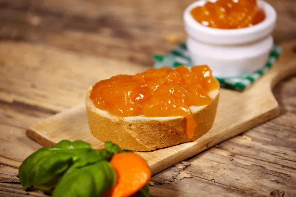 Orangenmarmelade mit Brotscheibe auf Holztisch — Stockfoto