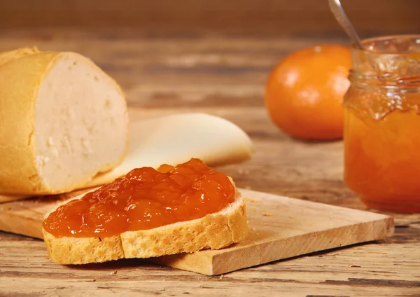 Mandarinenmarmelade mit Scheibe Brot auf Holztisch — Stockfoto