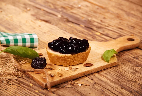 Mermelada de ciruela con pan sobre tabla de madera —  Fotos de Stock