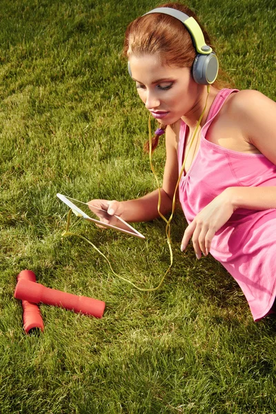 Young woman resting and listen to music after exercising in the — Stock Photo, Image