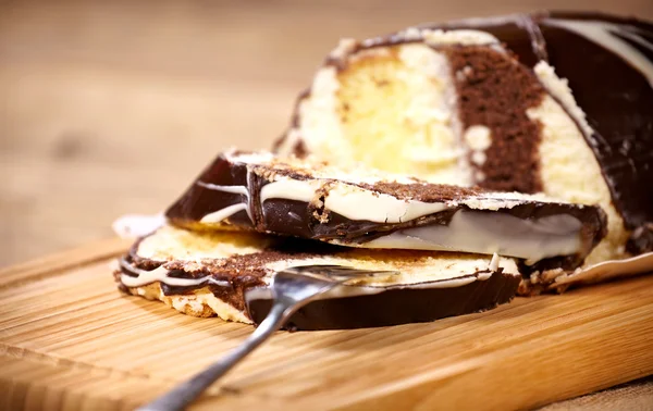 Schokoladenkuchenrolle mit Vanillecreme auf einem Holzbrett — Stockfoto