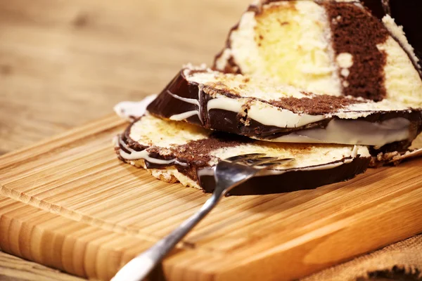 Schokoladenkuchenrolle mit Vanillecreme auf einem Holzbrett — Stockfoto