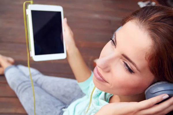 Young woman listens to music on tablet — Stock Photo, Image