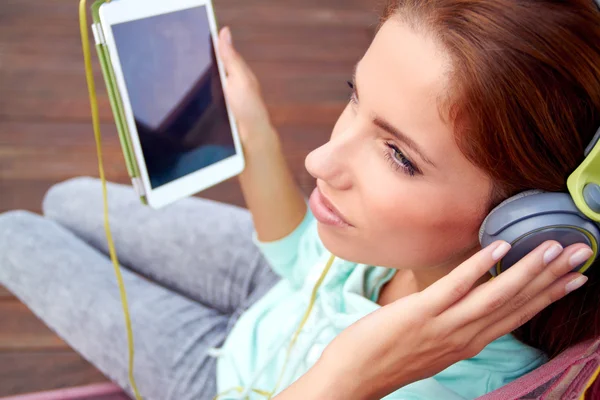 Young woman listens to music on tablet — Stock Photo, Image