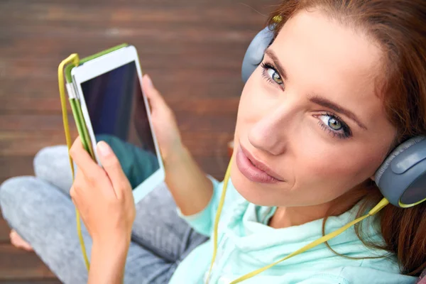 Young woman listens to music on tablet — Stock Photo, Image