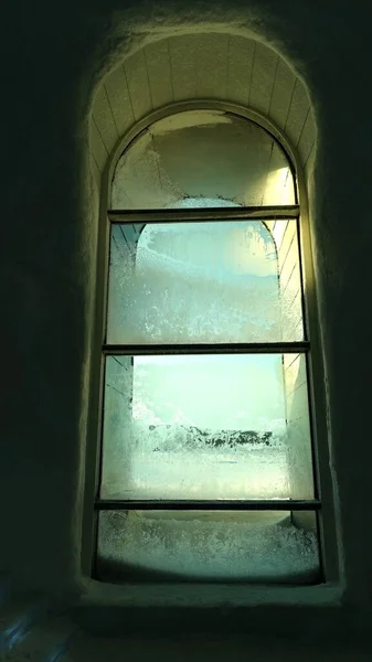 Окно, которое почти полностью покрыто кристаллами льда в солнечный день — стоковое фото