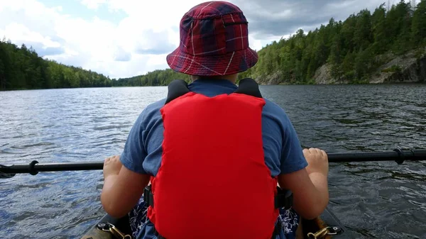 A man from behind, rests with his paddle in a canoe on the water — Stock Photo, Image