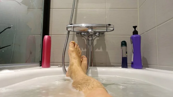 Feet sticking out of the water and soap suds during a hot bath — Stock Photo, Image
