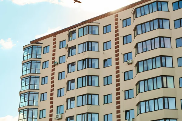 Daireler bloğu. Şehir emlakçılığı. Basit bir apartman mimarisi. Modern kum sıva cephesi, büyük bir pencere balkonu ve cam pencereleri var. Yeni apartman dairesi tipi.