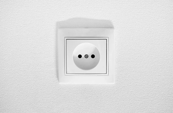 German circular recess socket with two round holes for 2 pins europlugs types C, E and F. Common cheap plastic AC power wall socket. Not grounded European white electrical outlet CEE 7 against wall — Stock Photo, Image