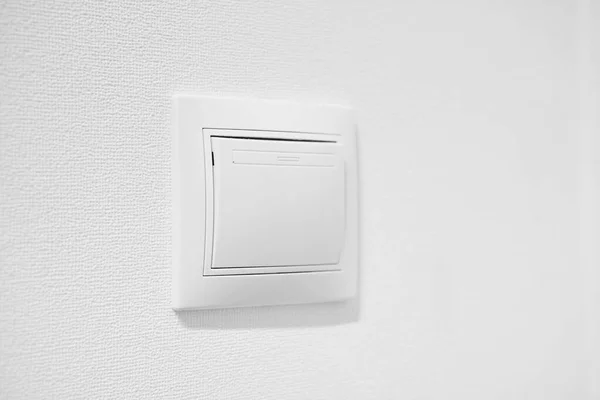 Standart rocker switch for exhaust fan or lighting applications. White common toggle switch in home. Inexpensive plastic push button switch against white wall. Cheap simple single-pole light switch — Stock Photo, Image