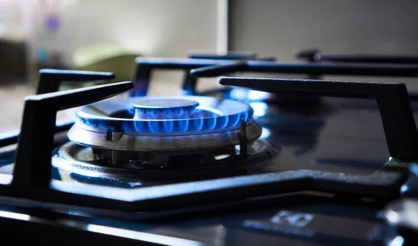 炉灶在可燃天然气或合成气、丙烷、丁烷等燃料的燃烧器上烤。气体滚筒发出的蓝色火焰产生温室气体排放。库克作为加热器。自然资源的经纪活动 — 图库照片