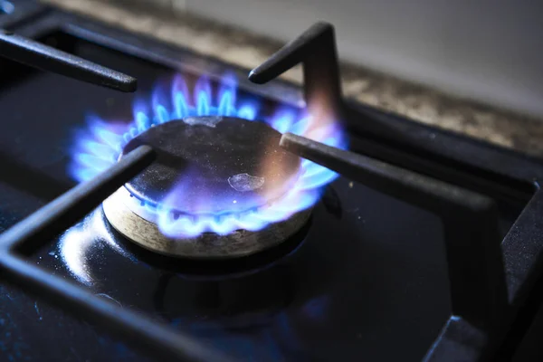 Estufa de cocina con quemador alimentado por gas natural de baja calidad combustible barato o syngas, propano, butano. La llama rojiza de la placa de gas pobre produce emisiones de gases de efecto invernadero. Desperdicio de recursos naturales — Foto de Stock