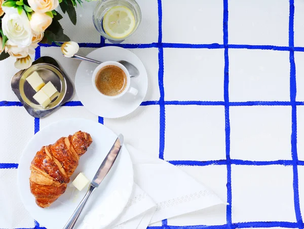 Snídaně Croissant Máslem Šálek Kávy Vody Citronem Skle Kostkovaném Pozadí — Stock fotografie