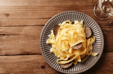 Tagliatelle İtalyan makarnası. Arka planda taze siyah trüf mantarı var..