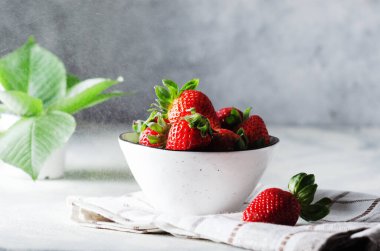 Taze çilek beyaz seramik kâse üzerinde kareli peçete.