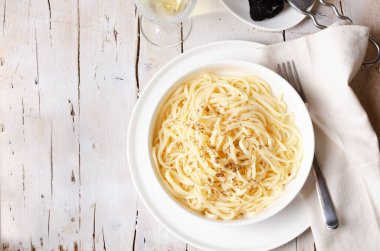 Cacio e Pepe - İtalyan makarnası rendelenmiş Pecorino Romano peyniri ve kara biberle birlikte beyaz bir tabakta beyaz ahşap arka planda spagetti. En üstteki düz yerde. Boşluğu kopyala.