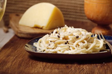 Cacio e Pepe - İtalyan makarnası rendelenmiş Pecorino Romano peyniri ve siyah biberle birlikte ahşap bir tabakta spagetti. Kapat, düzleştir, boşluğu kopyala.