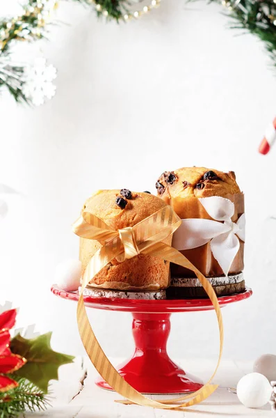 Traditional Italian Christmas sweet bread mini Panettone and Christmas decorations on a red plate on white background. Copy space.