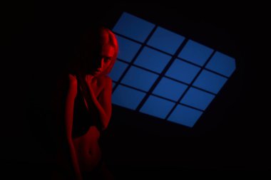 Kırmızı ışıkta poz veren güzel kız. Bir modelle alışılmadık bir fotoğraf oturumu.