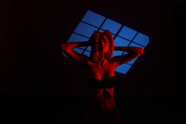 Beautiful girl posing in red light. Unusual photo session with a model.