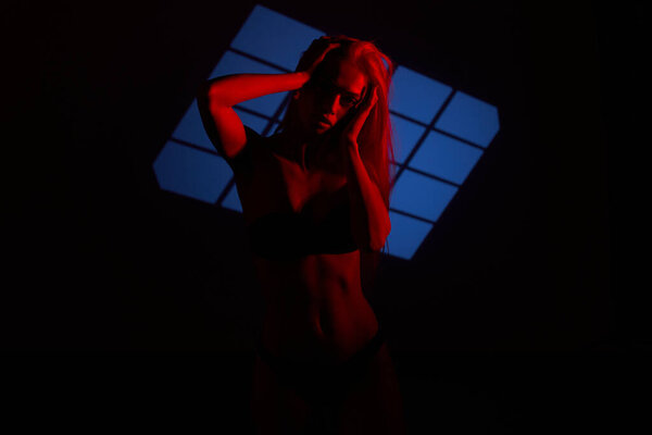 Beautiful girl posing in red light. Unusual photo session with a model.
