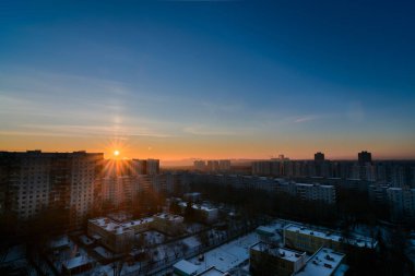 Güneşin doğuşuyla, kışın soğuk şehrin üzerinde aydınlık sütunlarla