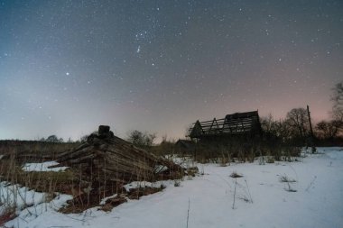 Terk edilmiş bir köy. Kış gecesi gökyüzünde yıldız izleri var.