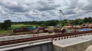 Railroad construction site view with HD footage in a rural area. Bridge construction video with a cloudy sky and village background. HD Motion footage of a rail road construction with a drone.