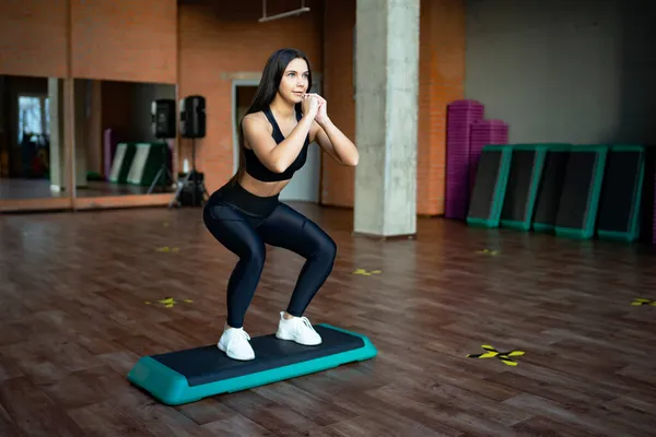 Young woman exercising in the gym, doing exercises shakes the buttocks and ass, leg lunges to the squat. fitness gym workout