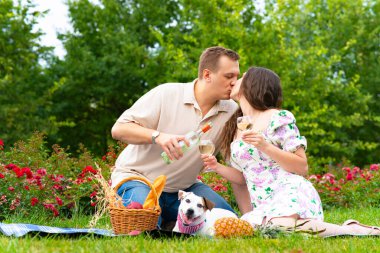 Sevgili kadın ve erkek öpüşüyor, elinde şarap kadehleri, köpeği gezdiriyor. Romantik bir aile, bahçede öpüşen bir çift.
