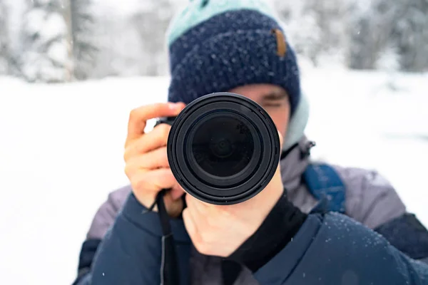 Un hombre toma fotos en la calle con una cámara analógica, una lente de primer plano, un fotógrafo. El tipo fotografía el paisaje invernal — Foto de Stock