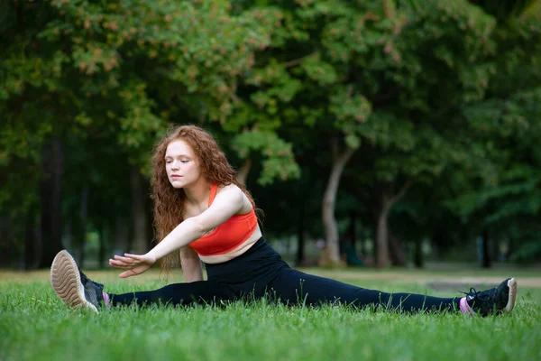 Genç bir kadın çimlerin üzerinde geriniyor. Parkta yaz sporları, sağlıklı yaşam tarzı.. — Stok fotoğraf