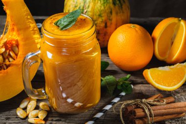 Nane yapraklı balkabağı püresi, bir parça çiğ balkabağı ve portakallı kavanozda ahşap arka planda nane yaprağı. yatay yönelim.