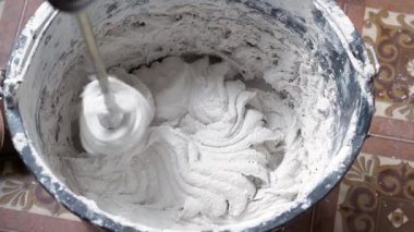 Bir insan, karışımı tamamlamak için çimento ve suyu bir kabın içine karıştırır..