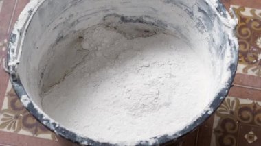 Bir insan, karışımı tamamlamak için çimento ve suyu bir kabın içine karıştırır..