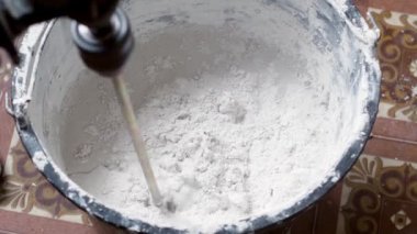 Bir insan, karışımı tamamlamak için çimento ve suyu bir kabın içine karıştırır..