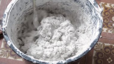 Bir insan, karışımı tamamlamak için çimento ve suyu bir kabın içine karıştırır..